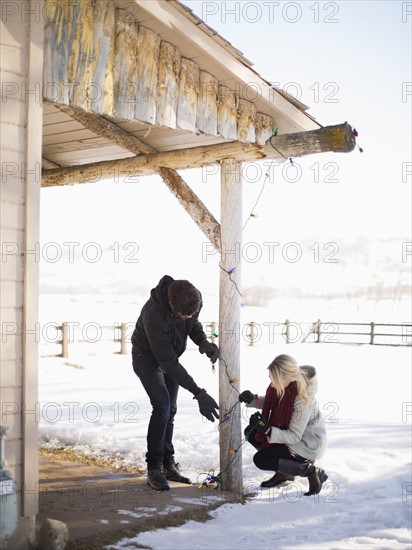 Young couple decorating house with christmas lights