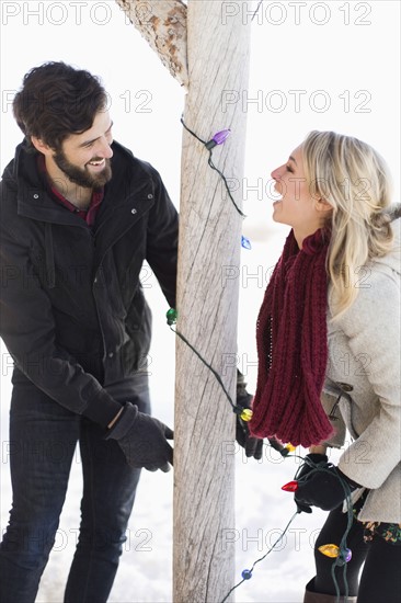 Young couple decorating house with christmas lights