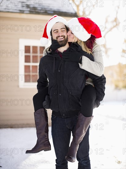 Portrait of young couple in santa hats, piggyback