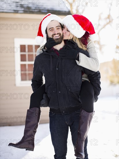 Portrait of young couple in santa hats, piggyback