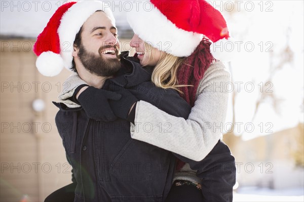 Young couple in santa hats, piggyback