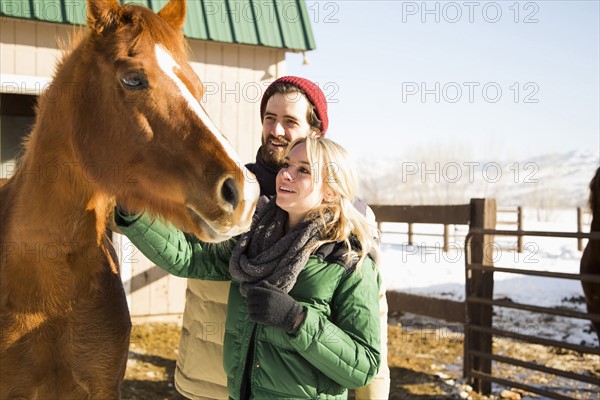 Young couple stroking horse