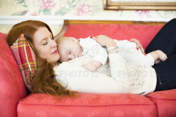 Mid adult woman napping with her baby boy (2-5 months)