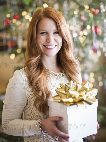 Studio shot of mid adult woman holding present in Christmas time