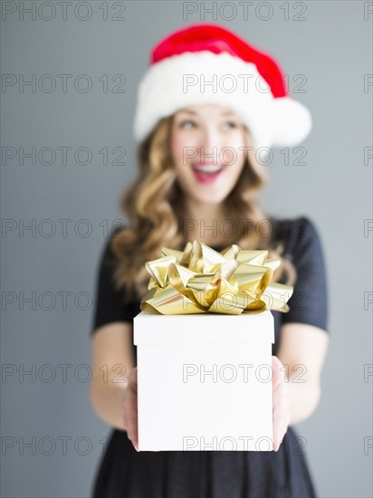 Studio portrait of woman wearing Santa hat holding gift