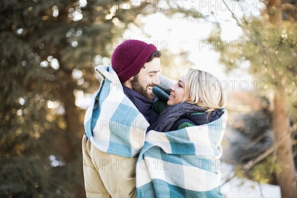 Couple wrapped in blanket hugging outdoors