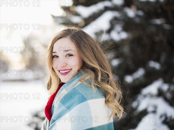 Portrait of woman wrapped in blanket smiling outdoors