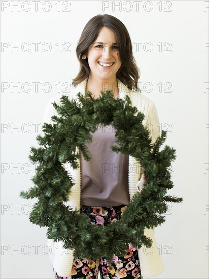 Studio shot of woman holding Christmas wreath