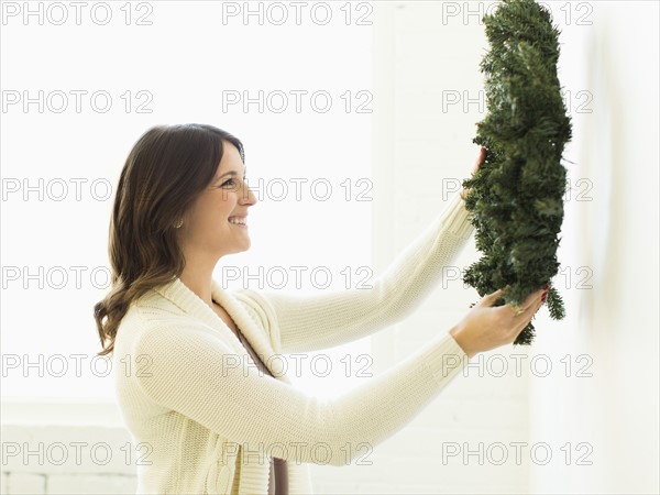 Woman decorating home with Christmas wreath