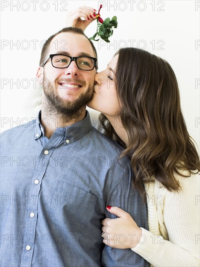 Woman kissing man under mistletoe