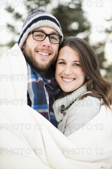 Portrait of couple wrapped in blanket smiling outdoors