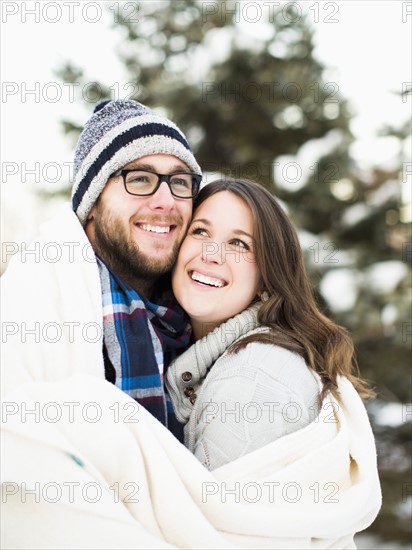Portrait of couple wrapped in blanket smiling outdoors