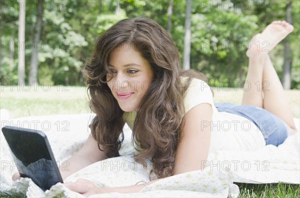 Woman lying on blanket using digital tablet