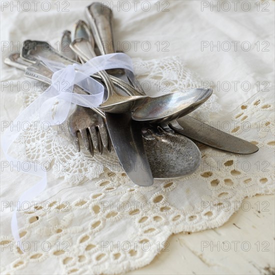 Studio shot of cutlery on lace cloth.