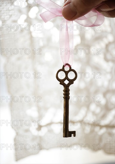 Studio shot of hand holding antique key.