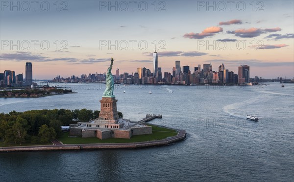 Aerial view of city with Statue of Liberty at sunset. New York City, New York.
