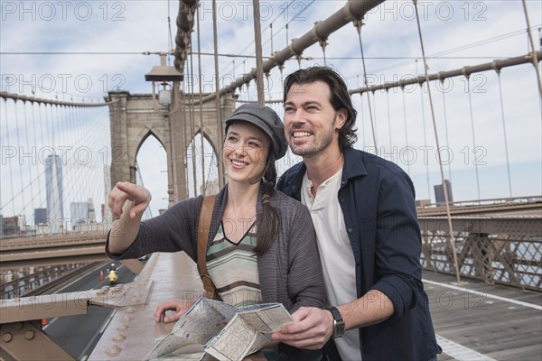 Happy couple with map on Brooklyn Bridge. Brooklyn, New York.