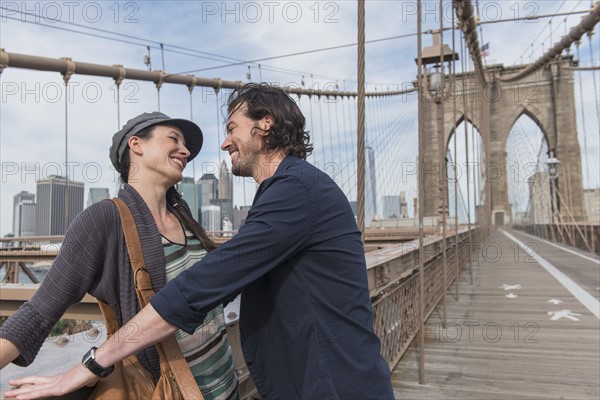 Happy couple flirting on Brooklyn Bridge. Brooklyn, New York.