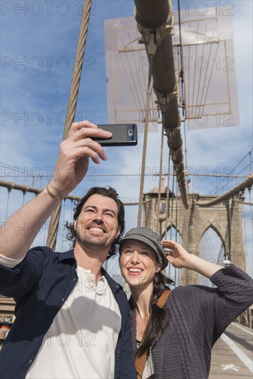 Happy couple taking selfie on Brooklyn Bridge. Brooklyn, New York.