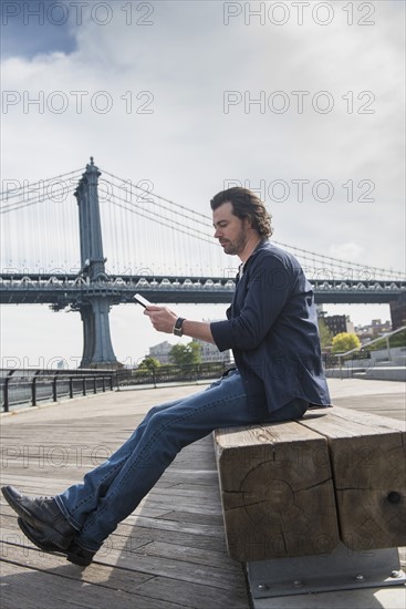 Man using tablet pc, Manhattan Bridge in background. Brooklyn, New York.