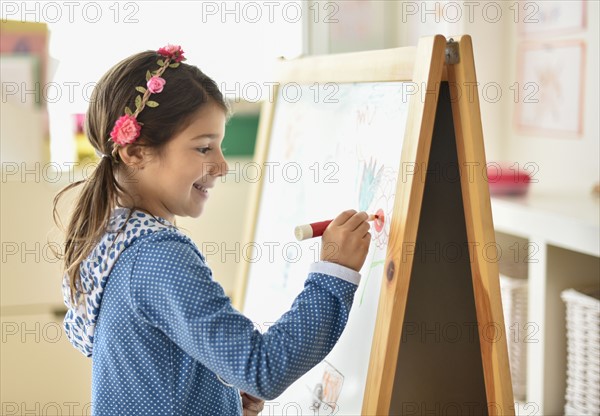 Girl (6-7) writing on board in classroom.