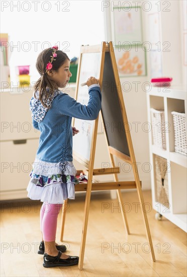 Girl (6-7) writing on board in classroom.