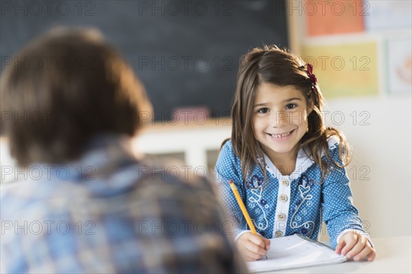 Pupils (6-7) learning in classroom, Girl (6-7) looking at camera.