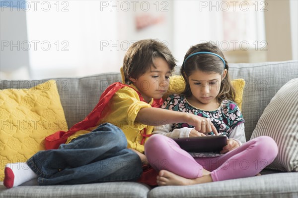 Children (6-7) playing game on tablet pc at home.