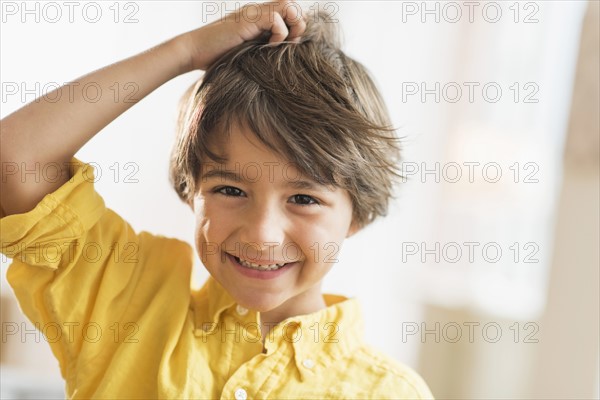 Portrait of smiling boy (6-7) with hand in hair.