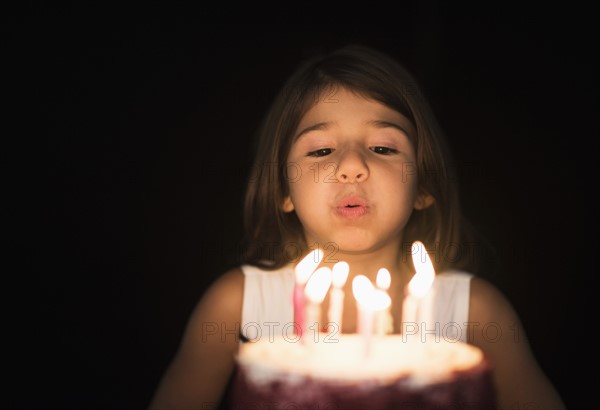 Portrait of girl (6-7) blowing out birthday candles.