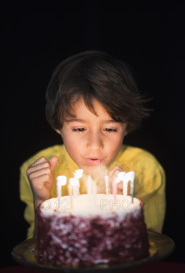 Portrait of boy (6-7) blowing out birthday candles.