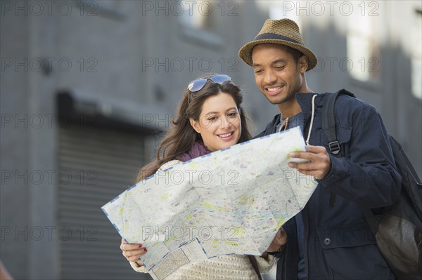 Couple reading map on street.