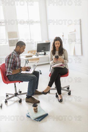 Couple sitting and working in office.