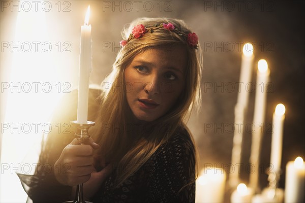 Sorceress holding candle in dark room.