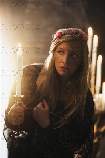 Sorceress holding candle in dark room.