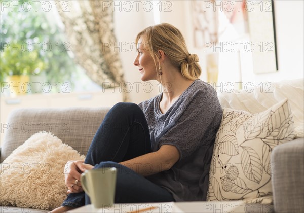 Woman sitting on sofa in living room.
