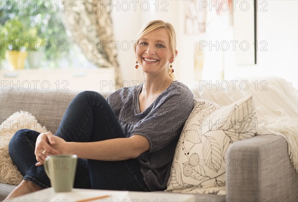 Woman sitting on sofa in living room.