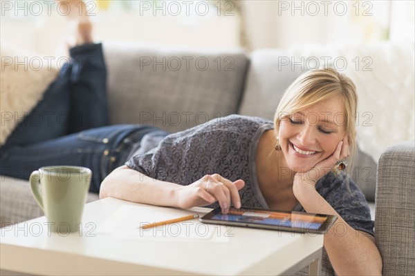 Woman lying down on sofa with tablet pc.