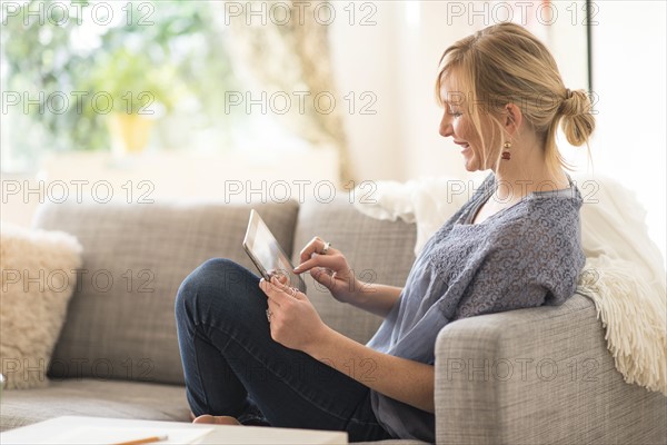 Woman sitting on sofa and using tablet pc.