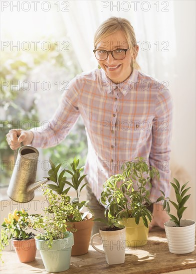 Woman watering plants in living room.