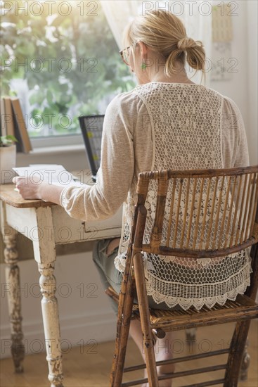 Rear view of woman working with laptop.