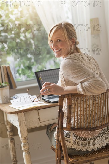 Smiling woman sitting at desk and looking over shoulder.