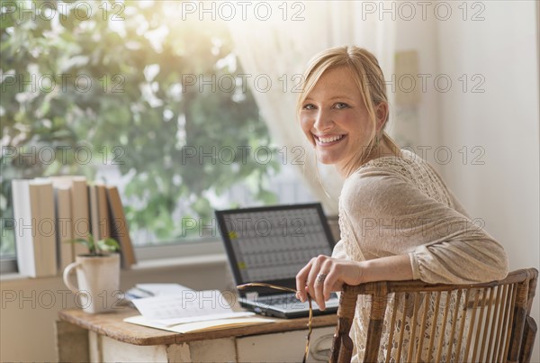 Smiling woman sitting at desk and looking over shoulder.