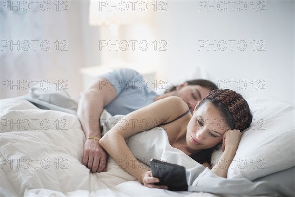 Couple in bed, Man sleeping, Woman using tablet pc.