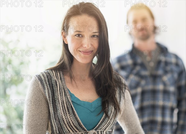 Smiling woman looking at camera, man in background.