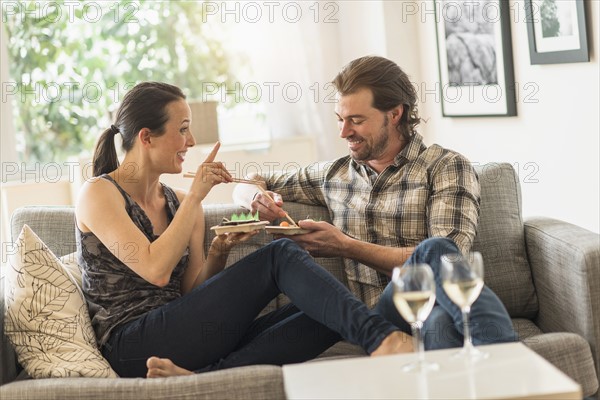 Cheerful couple eating on sofa.