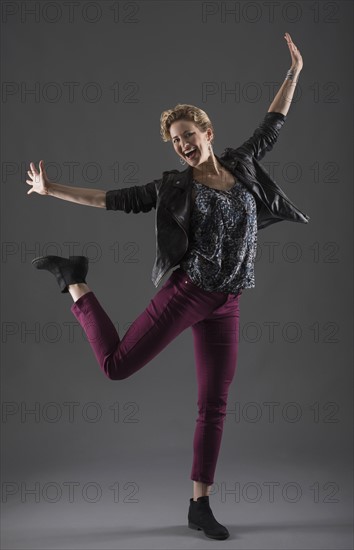 Studio shot of cheerful woman with arms raised.