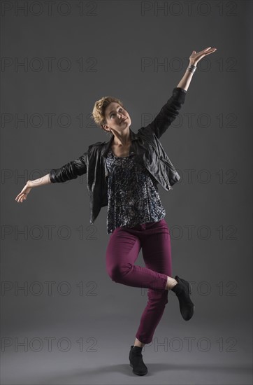 Studio shot of cheerful woman with arms raised.