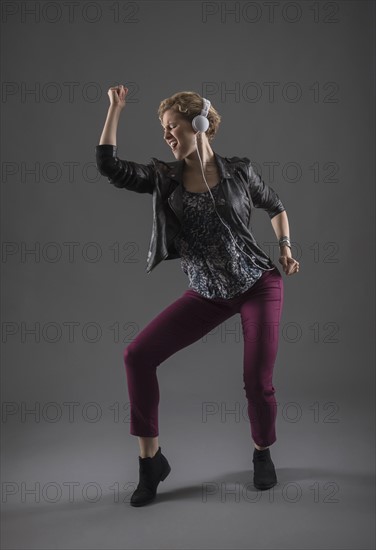 Studio shot of woman listening to music and dancing.