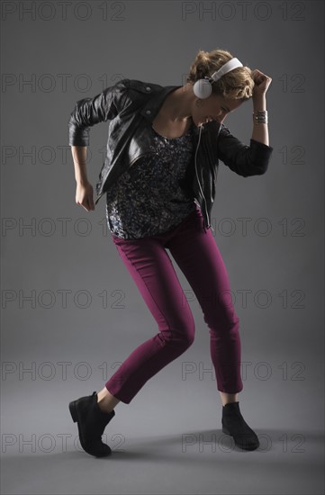 Studio shot of woman listening to music and dancing.